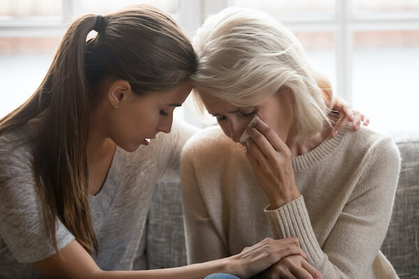 Mother reaching out to daughter for support while bereaved