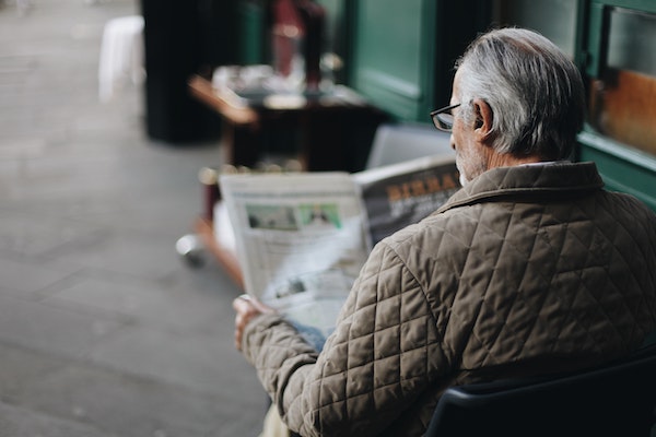 Man reading obituary section of the newspaper